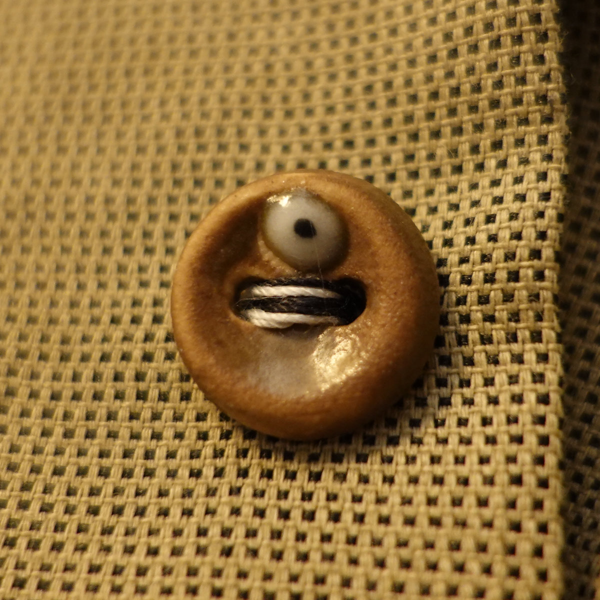 Ceramic sewing button with a single glassy eye